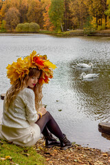 Beautiful girl in a wreath of autumn leaves.