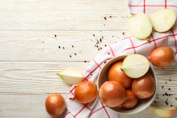 Bowl with fresh onion and napkin on wooden background