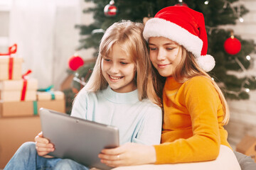 Two teenage girls with blonde European looks chat with friends and grandparents on Christmas Day. Social distancing on New Year's Eve.
