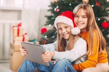 Two teenage girls with blonde European looks chat with friends and grandparents on Christmas Day. Social distancing on New Year's Eve.