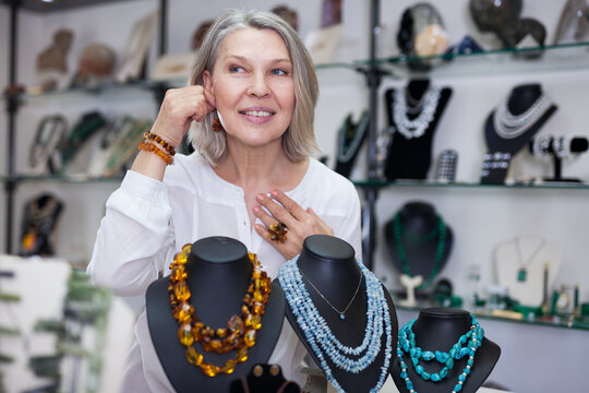 Woman trying on a aventurine necklace and earrings at a jewelry store. High quality photo