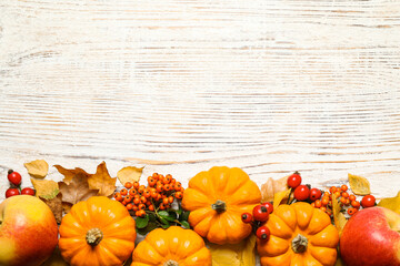 Flat lay composition with ripe pumpkins and autumn leaves on white wooden table, space for text....