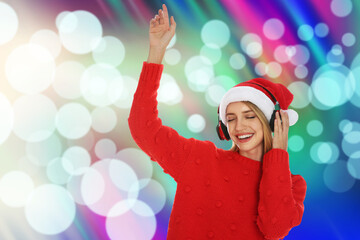 Happy woman in Santa hat listening to Christmas music with headphones on bright background, bokeh...
