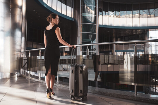 Elegant woman wearing a black dress and holding a suitcase