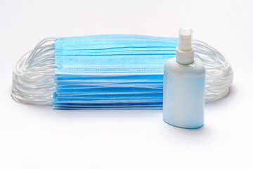 bottle of lotion, sanitizer or liquid soap and medical protective masks over light grey background