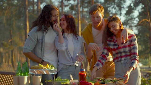 Group Of Young Men And Women Enjoying A Picnic In Nature.