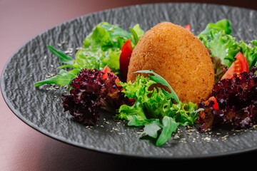 Oval cutlet with vegetables and salad on wooden background