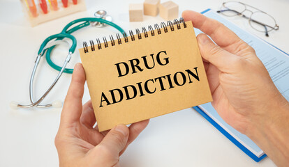 Notepad with text Drug Addiction in the hands of a doctor and a stethoscope