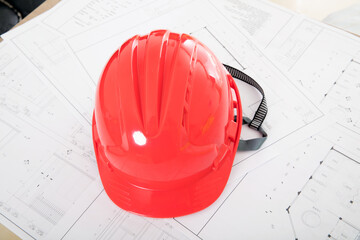 Red safety helmet placed on construction drawings
