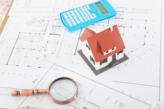 House Model And Calculator And Magnifying Glass On Floor Plan