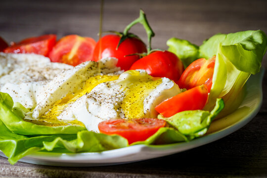 Italian buffalo mozzarella cheese with cherry tomatoes and extra virgin olive oil served on green lettuce leaves
