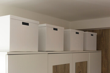 Large white cardboard boxes on a white closet in the bedroom. Storage in a minimalist interior