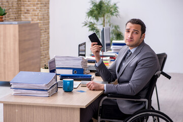 Young male enployee in wheel-chair at workplace