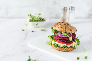 Vegan burger with beetroot cutlet and micro greens on white background.