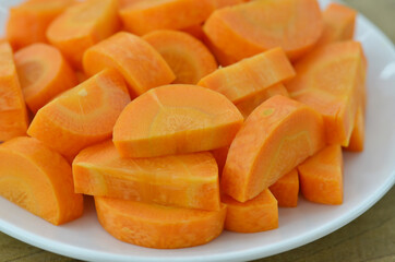 Cut carrots thick in white plate on wooden background