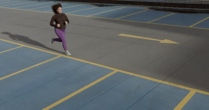 Body positive black female runner exercising outdoors on urban road, Plus size obese overweight black woman sports training on car park in city