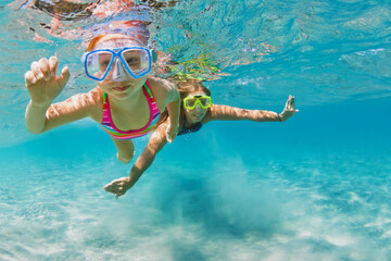 Young mother with child in snorkeling mask dive in coral reef sea lagoon to explore underwater world. Family travel lifestyle in summer adventure camp. Swimming activities on beach vacation with kids. - obrazy, fototapety, plakaty