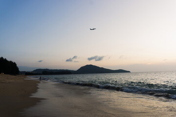 Beautiful evening sea waves, shadow of fisherman and airplane, Mai Khao Beach, Phuket, Thailand..