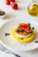 Polenta with mozzarella, bacon and tomatoes. Italian cuisine. Recipe.