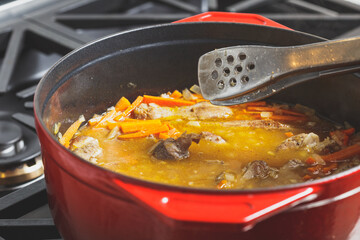 Pilaf cooking process at home in a red dutch oven