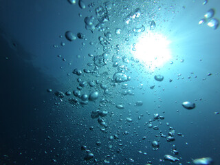 Burbujas bajo el mar azul con sol