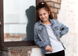 portrait of a beautiful teenage girl posing against a brick wall and window