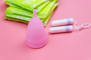 Sanitary pad, tampons and menstrual cup on pink background. Concept of critical days, menstruation, feminine hygiene