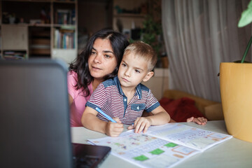 Distant education. Mother doing online homework with her little son at home, family lifestyle