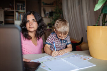 Distant education. Mother doing online homework with her little son at home, family lifestyle