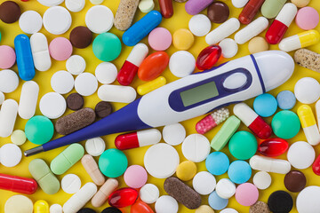 Pills and electronic thermometer with blank screen - medical background