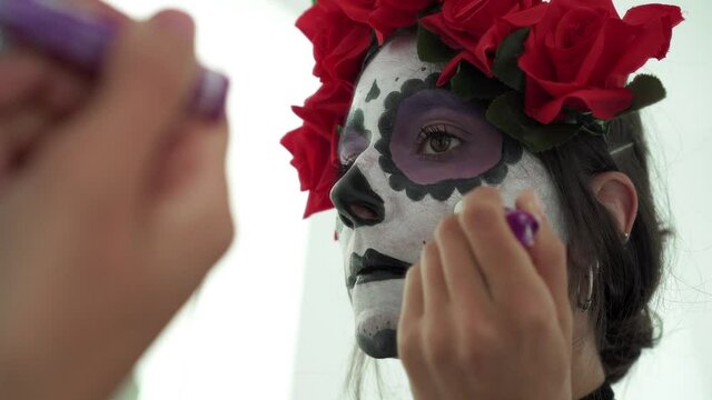 Concepto de Carnaval o Halloween. Mujer maquillaje de calavera mexicana blanca en espejo, usa ropa negra en un escenario de miedo 4K