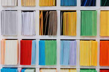 Envelopes stacks sorted on a shelf by color. Colorful mail wraps arranged in categories. Large...