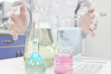 Selective focus of colorful liquid chemicals in glass beaker, flask and tube with scientist hands working. Chemistry Laboratory class experiment background with copy space.