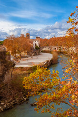 Fototapeta na wymiar Autumn and foliage along River Tiber. Beautiful red, orange and yellow leaves near Tiber Island in Rome historic center, seen from Palatine Bridge