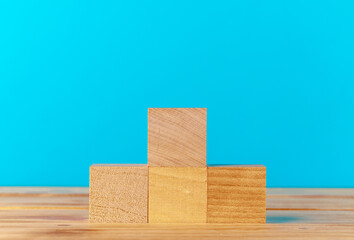 Stacked wooden blocks on wooden desk against blue background