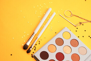 Professional eyeshadows and makeup brushes on a yellow background make-up decoration