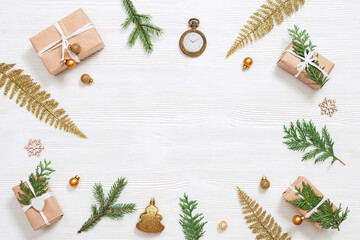 Homemade gift, Christmas present box wrapped in kraft paper, decorated natural green thuja branches, small golden balls on white wooden table