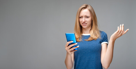 Disturbed girl has concerned face expression, holds smartphone, cannot understand whats wrong