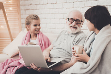 Children look at grandfather with a laptop.