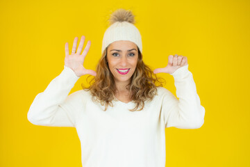 Young beautiful woman wearing winter clothes smiling happy and positive, thumb up doing excellent and approval sign