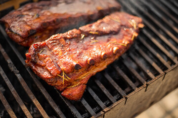 grilling baby back pork ribs over flaming grill.