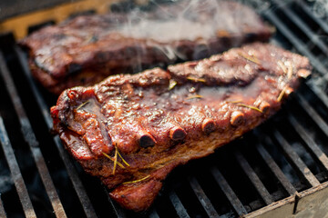 grilling baby back pork ribs over flaming grill.