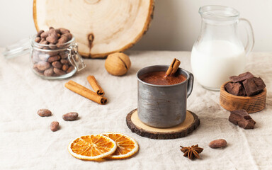 Hot chocolate in a metal mug with a cinnamon stick on the tablecloth. Copy space
