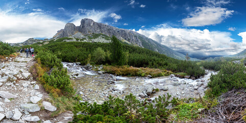 Panorama of tourist trail next to a creek in mountains