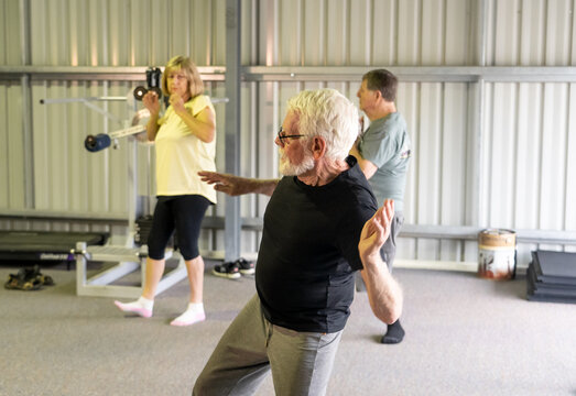 Group Of Elderly Senior People Practicing Tai Chi Class In Age Care Gym Facilities.