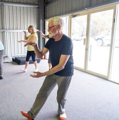 Group of elderly senior people practicing Tai chi class in age care gym facilities.