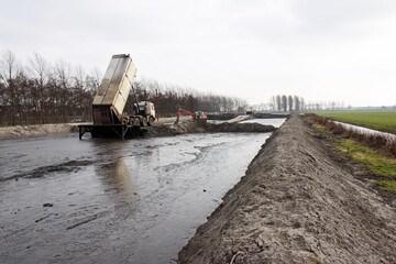 Truck unloading dredging spoil into a sediment storage basin © Roel