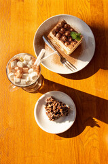 Cup of cocoa with marshmallows, a tiramisu cake and two pieces of chocolate chip cookies in a café on the table. Café concept.