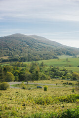 Fototapeta premium Bieszczady National Park. Curvy asphalt road. Idyllic autumn hills landscape. Travelling through southern Poland. Green meadow mountains background. Mountain road serpentines.