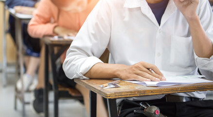 high school,university student study.hands holding pencil writing paper answer sheet.sitting lecture chair taking final exam attending in examination classroom.concept scholarship for education abroad